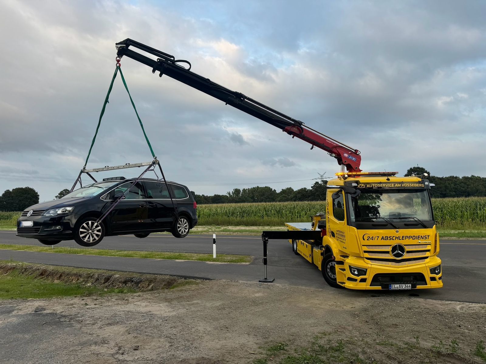 Gelber Kran-Abschleppwagen mit der Aufschrift 24/7 Abschleppdienst hebt einen Van an